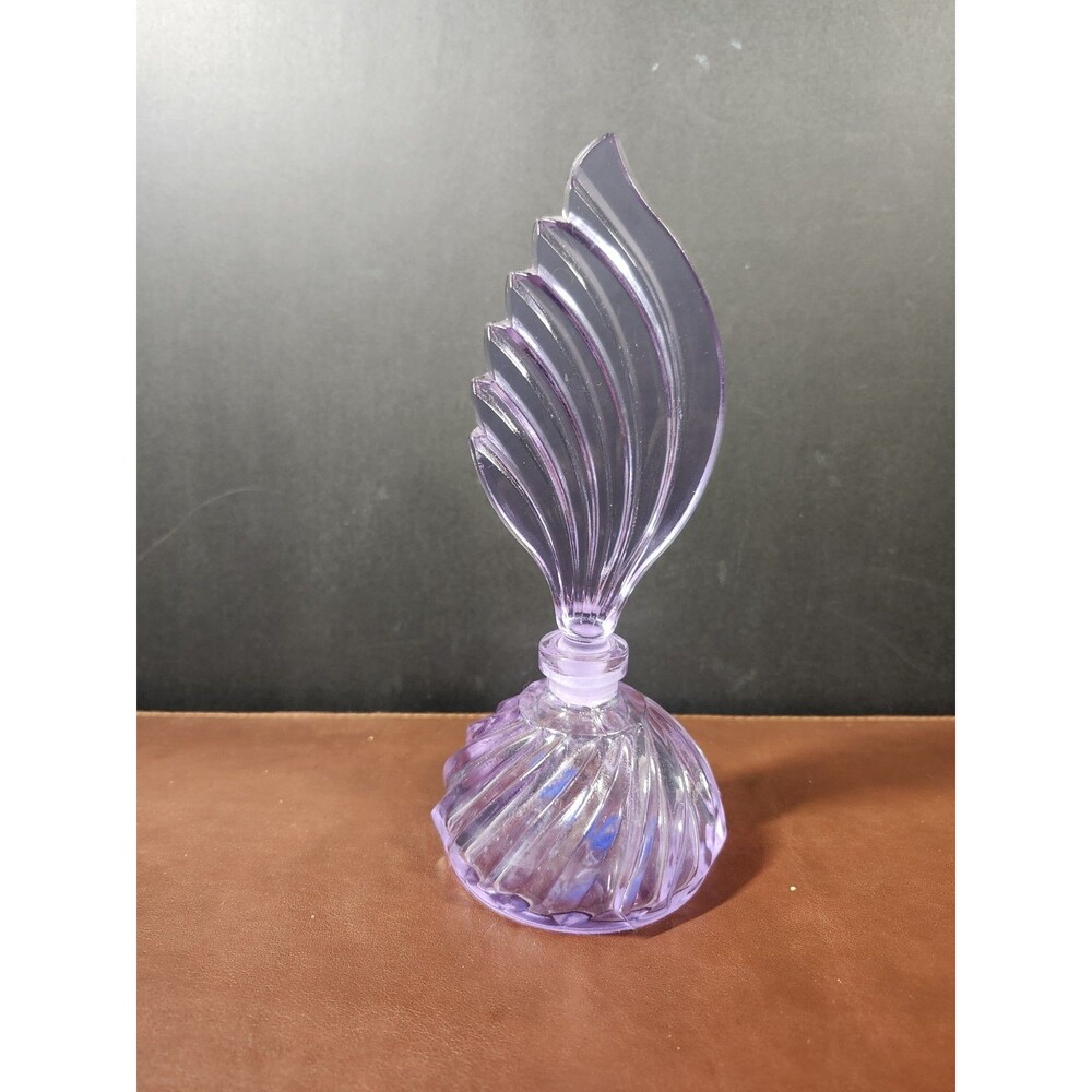 amethyst-colored glass perfume bottle featuring a distinct feather or...